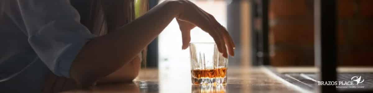 Woman is holding a glass filled with alcohol
