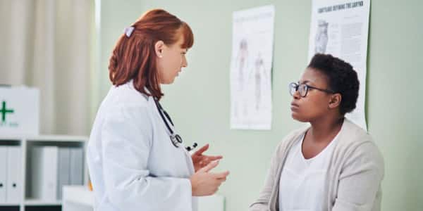A white doctor is talking to a black patient